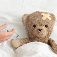 a teddy bear laying in a bed getting a shot.