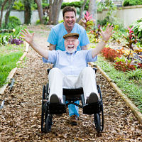 a nurse pushing a elderly patient in a chair.